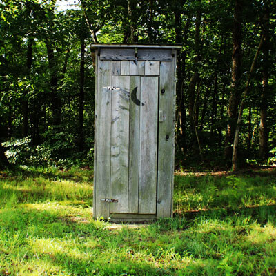 Eine Klokabine aus Holz auf einer Wiese